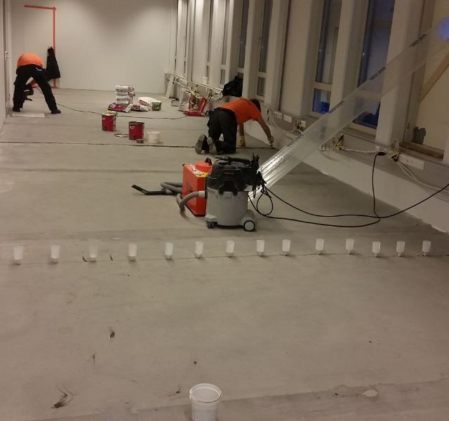 Työntekijät rakentavat liiketilan lattiaa