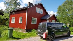 Musta pakettiauto vastamaalatun punaisen rintamamiestalon edessä